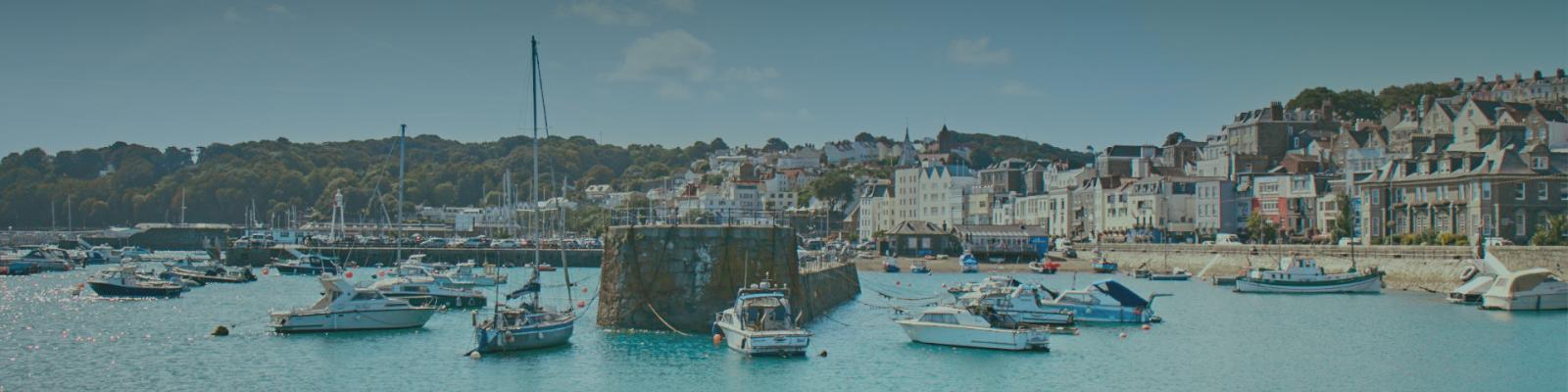 A view from sea of St Peter Port with boats mored up in the foreground